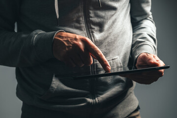 Closeup of male hands using digital tablet computer in low key light, browsing and working on touchscreen device at night.