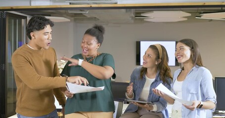 Pointing at paper, diverse coworkers exchanging ideas on project using tablet and trophy in office
