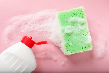 Kitchen sponge with foam and dish soap on pink background, flat lay