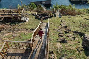 boy walking down wooden stairs near lake