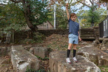 boy standing on boulder holding rock in air