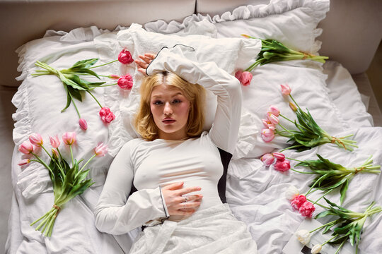 Woman resting in bed with flowers arranged around her on the sheets