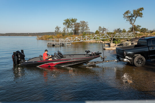 man launching bass boat at a sunny lakeside ramp