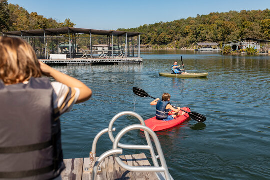 boy watching brother and dad kayak on lake