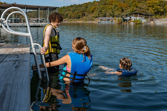teenagers and child swimming in lake by a swim dock