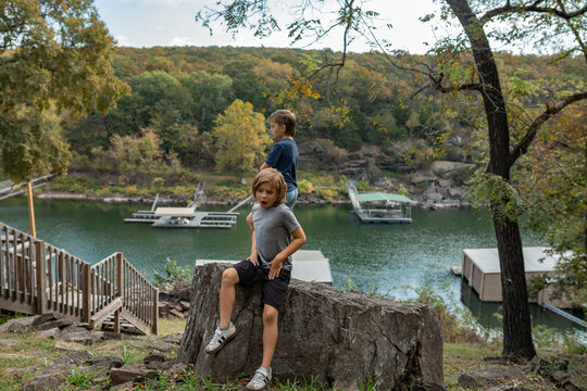 boys on a rock overlooking a calm lakeside dock area