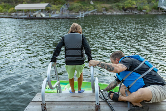 father helping son get into kayak on lake