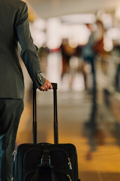 A business traveler pulls a suitcase through the bright airport.