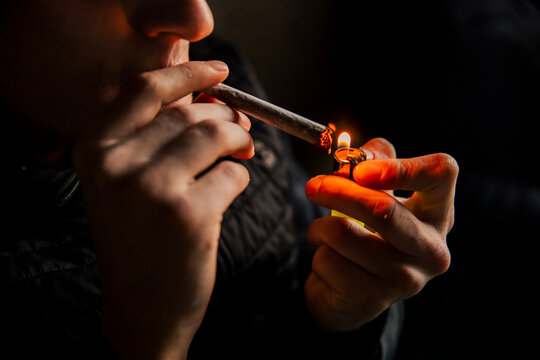 Close-up of a man lighting a marijuana cigarette with a lighter