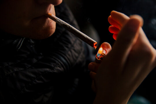 Close-up of a man lighting a marijuana cigarette with a lighter
