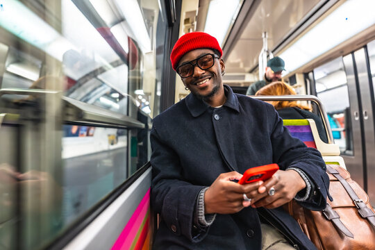 Young man smiling using phone while commuting by subway