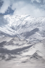 Fototapeta premium Landscape in the Pamir Mountains of Tajikistan with snow, glaciers, and cliffs, a panorama of mountains in cloudy weather for the background, nature in the Tien Shan highlands, landscape background