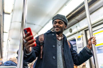 Young man commuting, enjoying using smartphone in subway