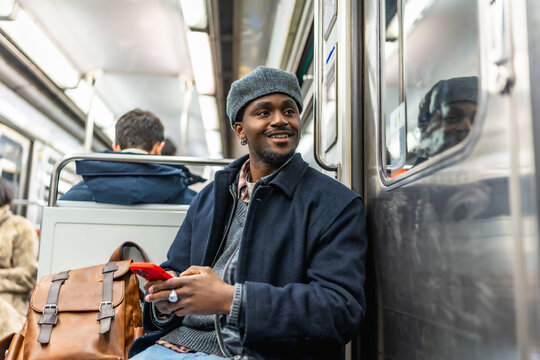 Young black man commuting in subway using smartphone - Powered by Adobe