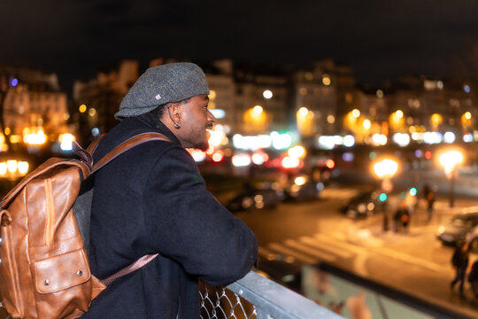 Young black man smiling observing paris city nightlife