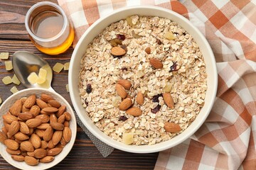 Making granola. Oat flakes, dried fruits, almond nuts and honey on wooden table, flat lay