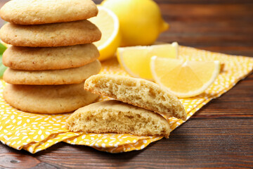 Tasty lemon cookies and fruit slices on wooden table, closeup