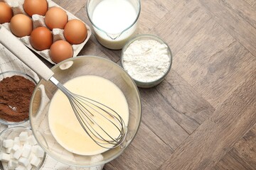 Different ingredients for dough and whisk on wooden table, flat lay. Space for text