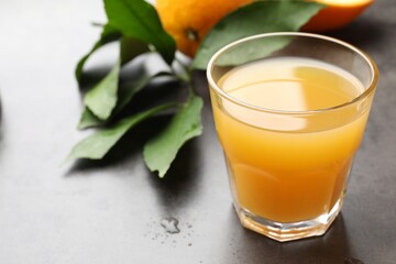 Fresh orange juice, fruits and leaves on grey table, closeup