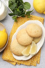 Tasty lemon cookies, mint, milk and fruits on light table, flat lay