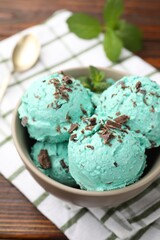 Tasty mint chocolate chip ice cream, spoon and towel on wooden table, closeup