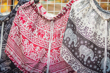 Colorful bohemian elephant pant shirts hanging on a market rack