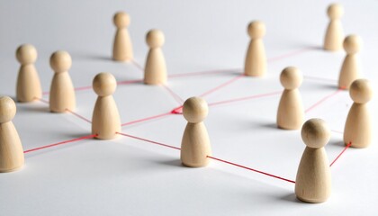 Wooden figurines connected by red strings form a network on a flat surface, symbolizing social systems, communication, and organizational relationships through a visual metaphor of interconnected node