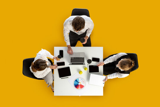 Coworkers drinking coffee while working with laptop and charts on white table. Concept of business routines, corporate communication, education visuals and marketing workflow. - Powered by Adobe