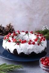 Tasty Christmas cake with cranberries, rosemary and festive decor on gray wooden table, closeup