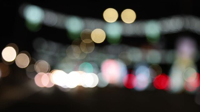 Defocused city traffic lights at night with cars passing by