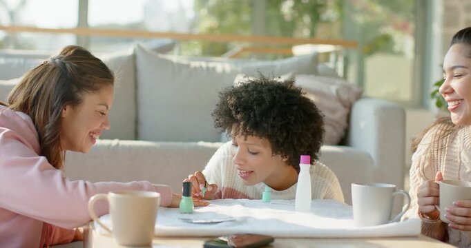 Diverse female friends spreading towel in living room and pampering nails with mint green polish