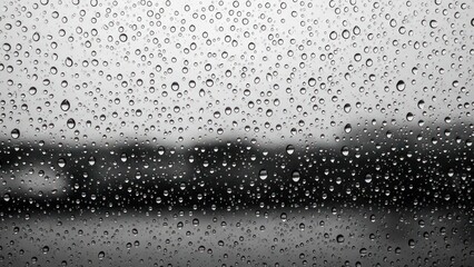 Obraz premium Raindrops cling to a window, blurring the landscape in the background