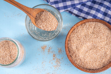 Whole Psyllium Husk in spoon, bowl and jar, with glass of water