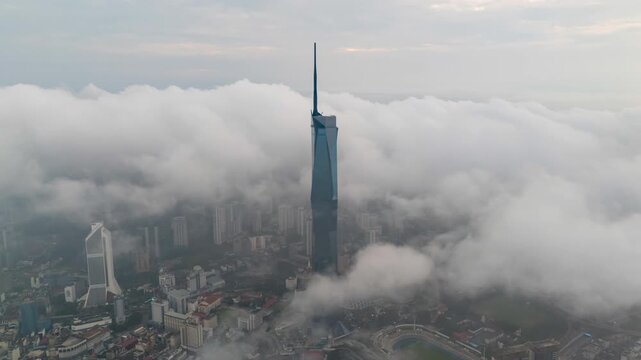Aerial view time lapse 4k video of Kuala Lumpur city center view during dawn sunrise overlooking the city skyline in Federal Territory, Malaysia with dramatic low cloud rolling.  