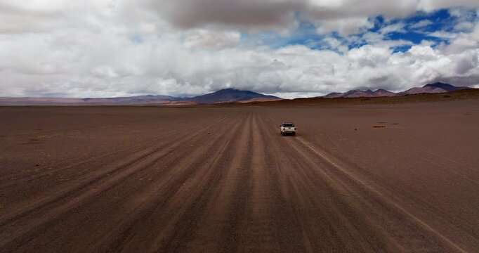 Drone follow car on plain and vast remote Siloli Desert in Bolivia. Road trip adventure, travelling