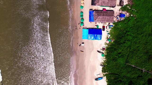 Colva beach shoreline with trees, Shacks, sunbeds and colorful umbrellas at goa. day time, bird eye view shot, drone shot, 4k.