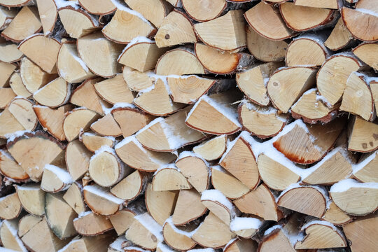 Firewood in a stack in the yard in January. A pile of firewood after a snowfall. Many Finnish detached houses are heated at least partially with firewood in the winter.