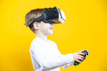 Youth Gaming Concept. Funny Caucasian Boy In Virtual Reality Helmet Holding Gamepad Joystick Pointing Forward With Lifted Hands Playing Game Isolated On Yellow Background