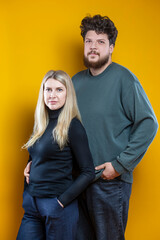 Obraz premium Lifestyle Concepts. Young Caucasian Smiling Happy Adorable Couple As Friendly Family Man And Woman Casual Clothing Together Embracing Cuddle Isolated on Seamless Yellow
