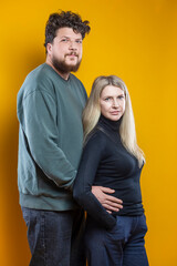 Obraz premium Lifestyle Concepts. Young Positive Caucasian Smiling Happy Adorable Couple As Friendly Family Man And Woman Casual Clothing Together Hugging Embracing Cuddle Isolated on Seamless Yellow Background