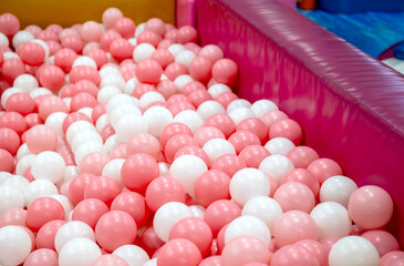 Toy ball, Pink and white play balls densely filling a ball pit, Plastic ball in a ballpit, Colorful ball in a playground, Creating a bright, Cheerful, Playful atmosphere ideal for kids themes and fun