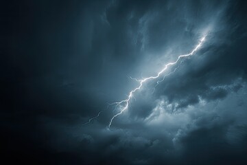 Dramatic image of powerful lightning bolt striking through turbulent, dark, stormy clouds