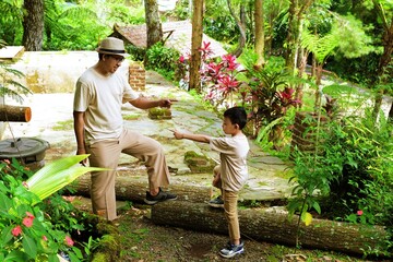 A father reaching out to his son in a green garden, capturing a warm and natural family interaction.