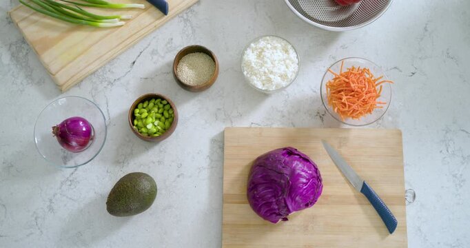 Overhead view showing counter with ingredients, colander appearing, receiving pepper and cucumber
