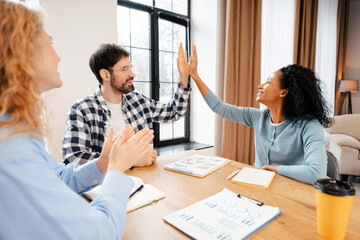 Diverse team celebrating success with high five and applause during office meeting