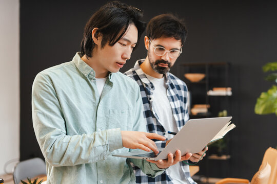 Diverse business colleagues collaborating on laptop in modern office space