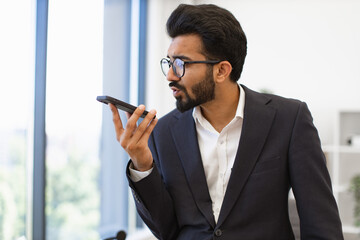 An Arab businessman in a suit speaks into his phone while working in an office setting