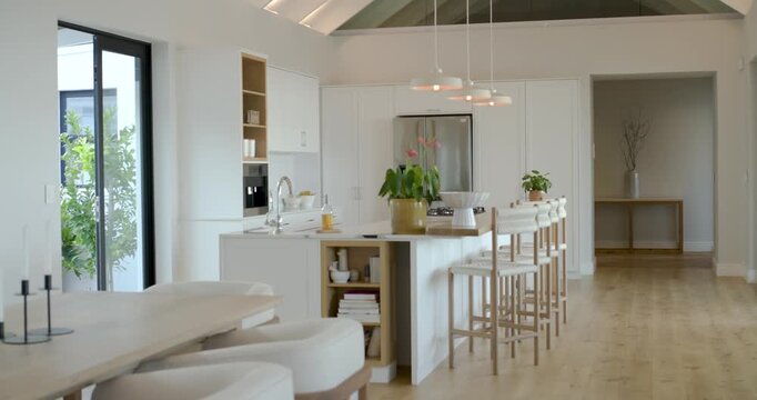 Camera is panning right revealing island, stools and dining table by sliding doors to show layout