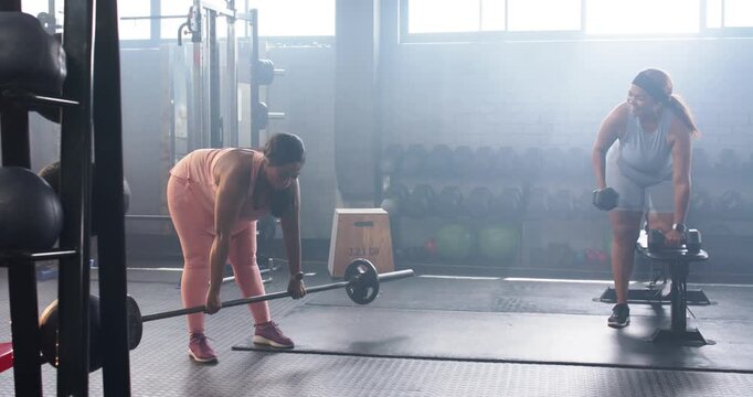 Diverse female partners starting set, hinging barbell and rowing dumbbell for back strength