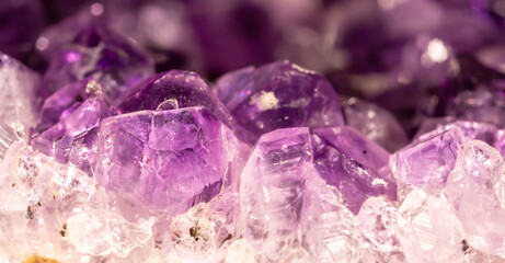 Fototapeta premium Amethyst purple crystals. Gems. Mineral crystals in the natural environment. Texture of precious and semiprecious stones. Seamless background with copy space colored shiny surface of precious stones.